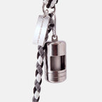 A silver dog poop bag holder attached to a black and white braided cord leash, featuring a silver metal tag engraved with 'JAMIE DOGWEAR'.