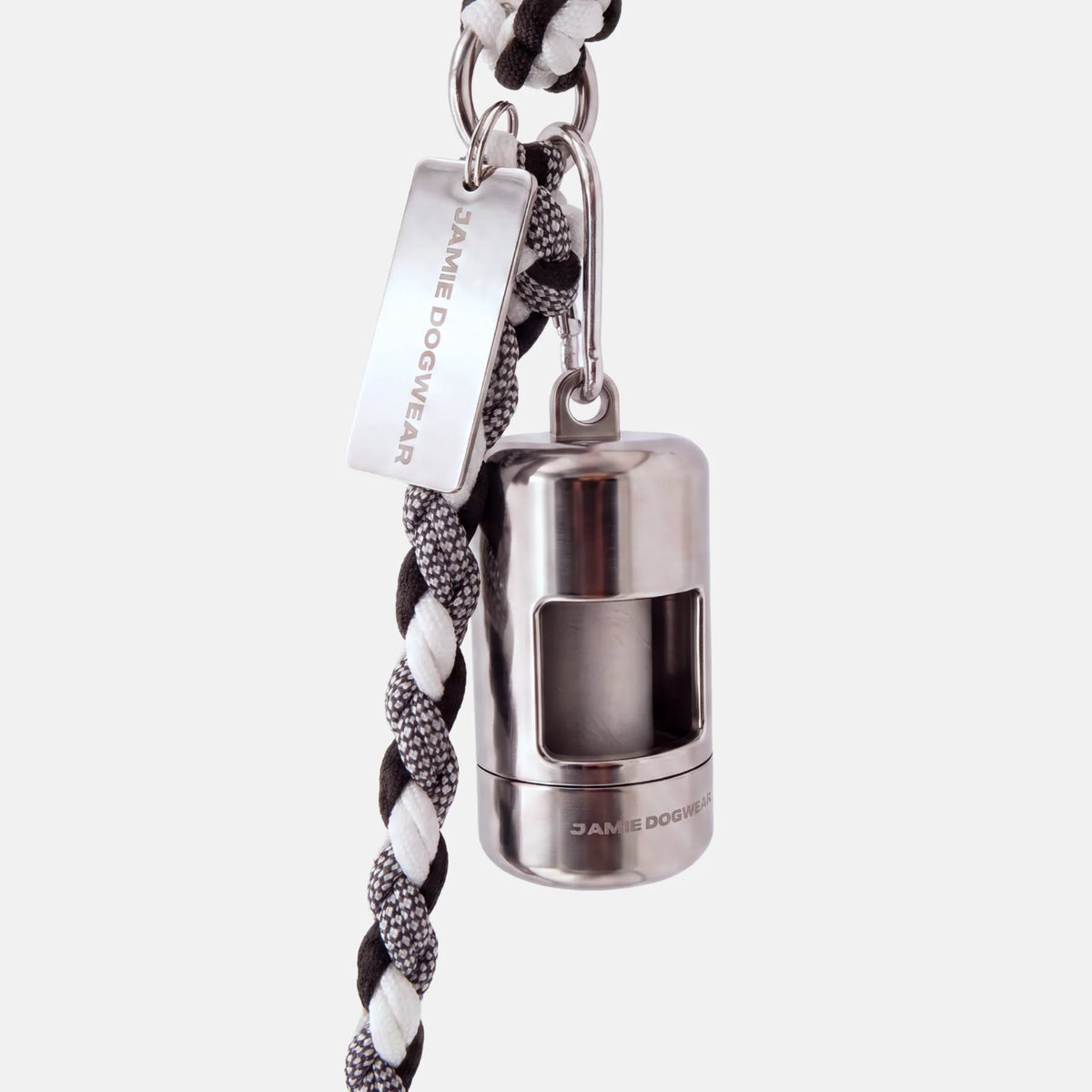A silver dog poop bag holder attached to a black and white braided cord leash, featuring a silver metal tag engraved with 'JAMIE DOGWEAR'.